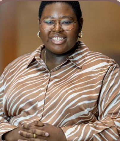 Headshot of Lanai wearing a brown and white patterned shirt against a brown backdrop. 